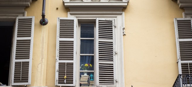 white window of old yellow house with books in the glass pane